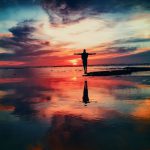 Self-healing Rubber - silhouette of person standing on rock surrounded by body of water