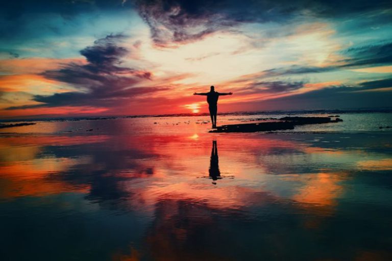 Self-healing Rubber - silhouette of person standing on rock surrounded by body of water