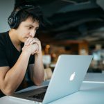 Ultra-efficient Vehicles - man wearing headphones while sitting on chair in front of MacBook