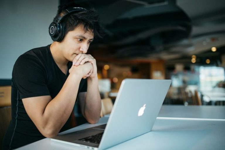Ultra-efficient Vehicles - man wearing headphones while sitting on chair in front of MacBook