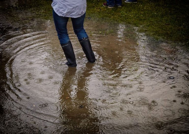 Rubber Adhesion - person with rain boots standing on body of water