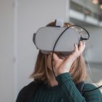 Education Programs - woman in black sweater holding white and black vr goggles