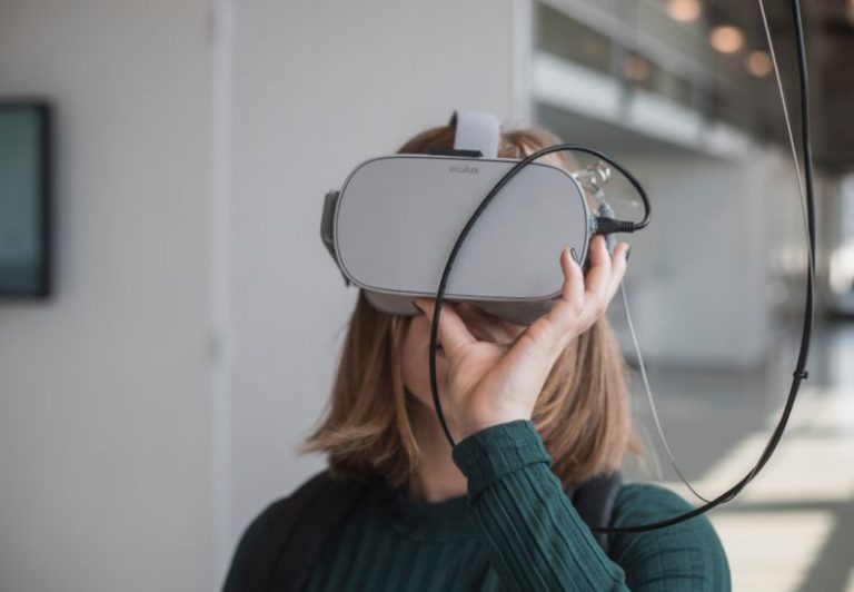 Education Programs - woman in black sweater holding white and black vr goggles