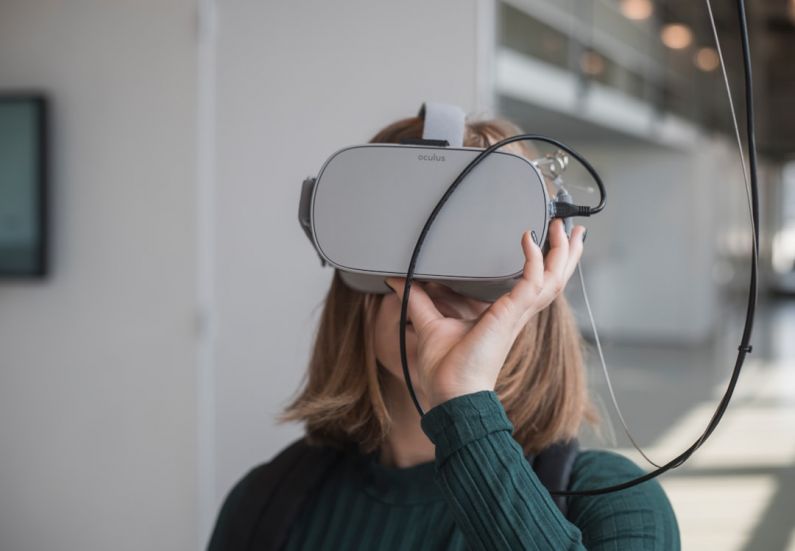 Education Programs - woman in black sweater holding white and black vr goggles