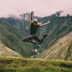 Tread Life - woman jumping on green mountains