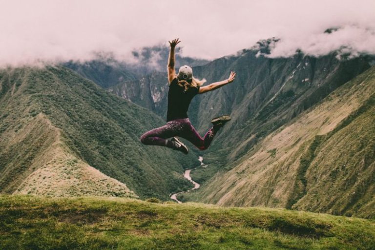 Tread Life - woman jumping on green mountains