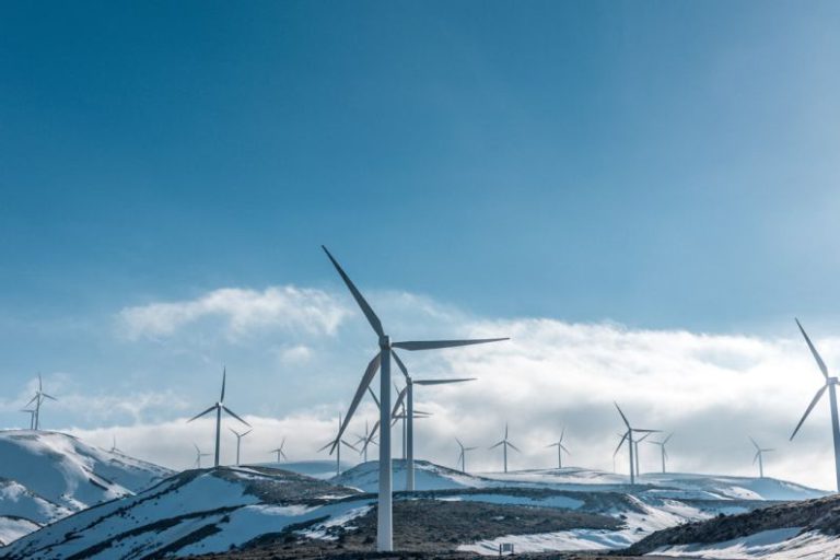 Energy Comparison - wind turbines on snowy mountain under clear blue sky during daytime