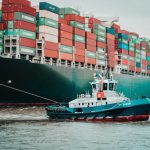 Supply Chain - a tug boat pulling a large container ship