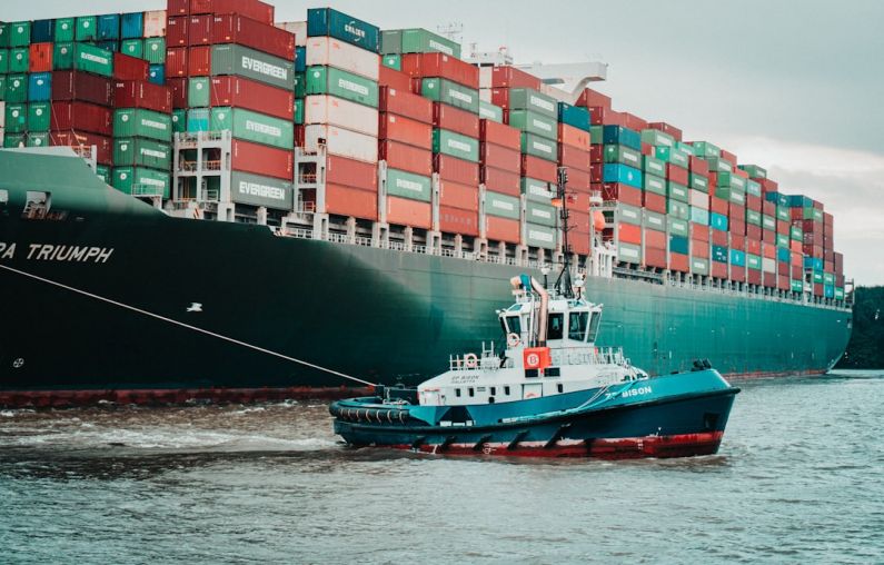 Supply Chain - a tug boat pulling a large container ship
